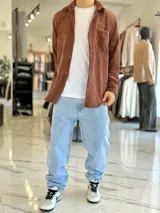 Sobrecamisa de pana color marrón chocolate, de manga larga, con cuello camisero, cierre frontal con botones y un bolsillo aplicado en el pecho.