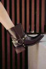 Bota corta de cuero color marrón oscuro, con hebilla dorada y arnés desmontable.