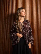 Blusa de gasa con estampado abstracto en tonos oscuros, cuello redondo con lazo ajustable, corte holgado con frunces y mangas largas abullonadas con puños elásticos.