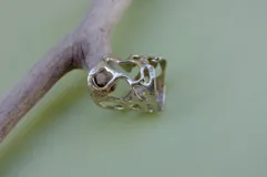 Anillo ancho de diseño orgánico y calado, con apariencia de red o magma solidificado.