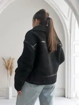 Campera negra de corderito con cuello solapa, cierre frontal con cremallera metálica y detalles de cuero sintético en cuello, solapa, cierre y bolsillos.