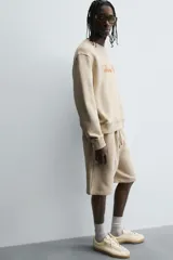 Bermuda de algodón color beige, estilo jogger, con corte relajado, cintura elástica ajustable con cordón y bolsillos laterales y trasero.