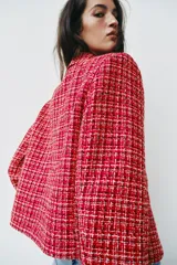 Blazer cruzado de tweed rojo con patrón texturizado en tonos blanco y negro, cuello con solapa, manga larga y cierre frontal con un botón.