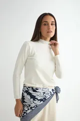 Polera de cuello alto y manga larga, confeccionada en tejido de punto fino de color blanco.