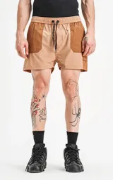 Short de baño de calce regular, color camel (marrón claro), con paneles de tela en tono marrón más oscuro en los bolsillos cargo laterales y en la parte superior de los bolsillos delanteros. Posee cintura elástica con cordón negro estampado.