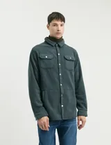 Sobrecamisa de micropolar color terracota, con cuello camisero, cierre frontal con botones a presión y dos bolsillos frontales con solapa y botón.