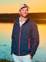 Campera impermeable liviana de hombre en color azul marino, con cierre frontal y bolsillos laterales con cierres en color rojo.