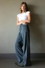 Jean de pierna ancha color gris oscuro, con cintura alta, bolsillos delanteros y traseros con detalle de trenzado, y cinturón de soga.