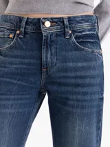 Jeans corte bootcut de tiro medio-bajo, confeccionado en denim azul con lavado desgastado y contrastes. Presenta cierre frontal con botón metálico y bolsillos laterales y traseros.
