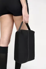 Bolso botinero negro con cierre superior y cinta de agarre.