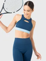 Top deportivo de entrenamiento con diseño de cuello alto y detalle de apertura frontal sobre el busto. Presenta una banda elástica inferior en tono celeste contrastante y almohadillas removibles.