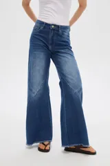 Pantalón jean gris de tiro alto, corte ancho (wide leg) con diseño de paneles tipo patchwork y terminación desmechada en el dobladillo.