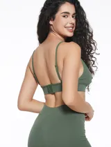 Top deportivo de estilo bralette, confeccionado en tejido seamless acanalado de color verde militar. Presenta escote en V, breteles finos y una banda elástica inferior con una pequeña etiqueta decorativa central.