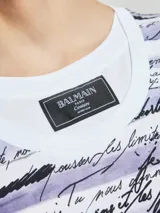 Remera de algodón blanca con estampado de texto en color lila y negro.