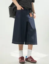 Bermuda baggy 3/4 de denim azul raw, con cintura semi-elástica en la parte trasera, cierre frontal con botón y bolsillos.