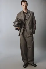 Pantalón de traje wide fit color marrón oscuro con textura, pinzas frontales, bolsillos laterales y cierre con cremallera y botón.