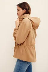 Campera estilo militar color tostado, confeccionada en 100% algodón, con cuello alto, cierre frontal de cremallera, bolsillos con solapa en el pecho y cordón ajustable en la cintura.