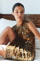 Vestido midi dorado cubierto de lentejuelas, con cuello redondo, mangas cortas y espalda abierta con cordones para ajustar.