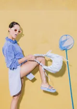 Bolso tipo cartera de nylon con diseño plisado y estampado abstracto en tonos claros.