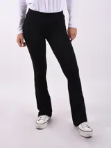 Calza de tiro alto en color negro, con corte ajustado en la parte superior y ligeramente acampanado en el bajo.