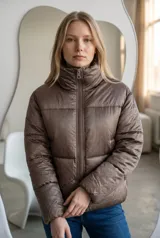 Campera puffer color bronce con cuello alto, cierre frontal y diseño acolchado con pequeños detalles brillantes distribuidos por toda la prenda.