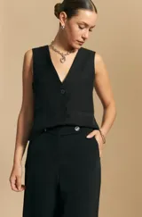 Pantalón ancho color tostado, de silueta fluida y cintura elastizada. Presenta una pretina ancha con botones metalizados irregulares.