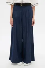 Pantalón de jean azul oscuro, tiro alto, corte ancho y holgado, con bolsillos y frunces en la cintura.