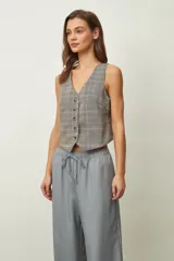 Chaleco corto de mujer con estampado de cuadros en tonos beige, gris y naranja, escote en V y cierre frontal con botones.