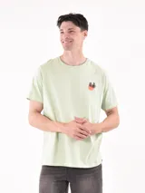 Remera verde claro de corte recto y mangas cortas, con estampado pequeño de palmeras y sol en el pecho.