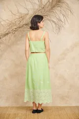 Conjunto de dos piezas compuesto por un crop top de breteles anchos y una pollera midi, ambos en color azul con detalles de bordado floral blanco en el ruedo y el lateral del top.