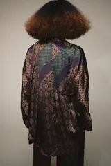 Camisa de seda con estampado tipo pañuelo en tonos marrones y ocres, cuello solapa, manga larga y detalle de pañuelo integrado en el cuello. Presenta bajo asimétrico y cierre frontal con botones.
