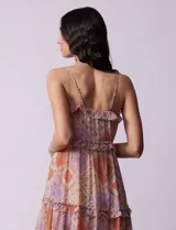 Vestido midi de gasa estampada con motivos geométricos en tonos naranja, lila y beige. Tiene breteles finos regulables, escote en V con volados y falda asimétrica con volados.