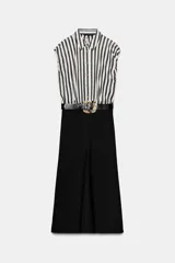 Vestido midi combinado con parte superior de camisa a rayas verticales blancas y negras, cuello solapa, manga sisa con frunces y botones dorados. La parte inferior es una falda midi negra de corte recto. Incluye un cinturón negro con textura de cocodrilo y hebilla dorada.