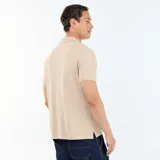 Remera polo de piqué de algodón en color beige, con cuello clásico y cierre frontal de tres botones.