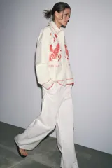 Sobrecamisa color crudo de Zara Woman Collection, con cuello solapa y manga larga. Tiene bolsillos de parche en el delantero y bordados combinados a contraste en color rojo. Cierre frontal con botones a presión ocultos.