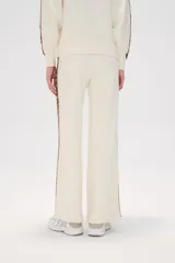 Pantalon de tejido de punto color crema, de corte ancho y tiro alto. Presenta una franja lateral con estampado animal print a lo largo de ambas piernas.
