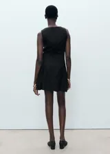 Vestido corto negro de corte evasé, confeccionado en mezcla de lino y lyocell. Presenta cuello barco, sin mangas con tirantes anchos, y detalle de pliegues en la falda. Cuenta con cierre de cremallera en la parte posterior.