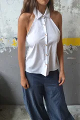 Top azul de corte halter, sin mangas, con cuello camisero y cierre frontal de botones coloridos.
