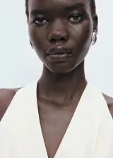 Mono largo de diseño recto y cuello halter con escote en pico. Presenta cierre frontal de botones, tirantes anchos y un cinturón ajustable tipo lazo en la cintura.