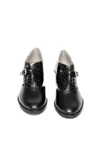 Zapato de tacón cuadrado color negro, confeccionado en cuero con combinación de texturas: efecto reptil en la parte trasera y cuero liso en la puntera. Presenta un diseño con aberturas laterales y cierre con hebilla dorada.