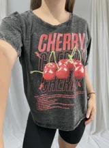 Remera negra con efecto gastado y estampado de cerezas rojas con texto.