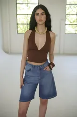 Bermuda de denim azul claro, de tiro medio y largo a la rodilla, con calce relajado y silueta amplia. Cuenta con bolsillos delanteros y traseros, y cierre frontal con botón y cremallera.