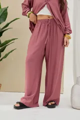 Pantalón largo color malva de corte ancho y relajado, con cintura elástica fruncida y cordón ajustable del mismo tono.