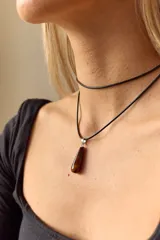 Gargantilla de cuero negro con dije de piedra blanca en forma de lágrima con engarce dorado.