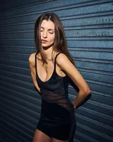 Minivestido negro con breteles finos, escote en V y corte ajustado. Presenta una sección de terciopelo brillante en la parte superior y una sección de tul transparente en la zona del abdomen.