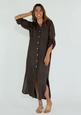 Vestido camisero largo color marrón oscuro, de lino, con botones blancos y mangas 3/4 con presilla. Tiene aberturas laterales en el ruedo.