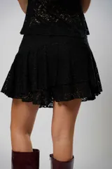 Pollera corta de encaje negro con diseño de volados escalonados y terminación con borde festoneado.