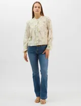 Blusa de algodón con estampado floral de flores silvestres sobre fondo claro. Presenta cuello redondo con detalle de puntilla, abotonadura frontal, canesú con frunces y mangas largas con puños elásticos decorados con puntilla.