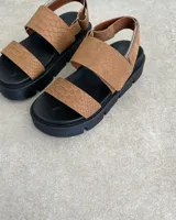 Sandalia de plataforma color camel con textura de piel de serpiente en las tiras superiores y suela track negra. Posee una tira de tobillo ajustable con cierre metálico.