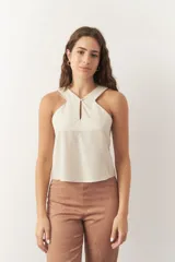 Musculosa negra de lino, sin mangas, con cuello halter cruzado, cut out en el frente y botón a tono.